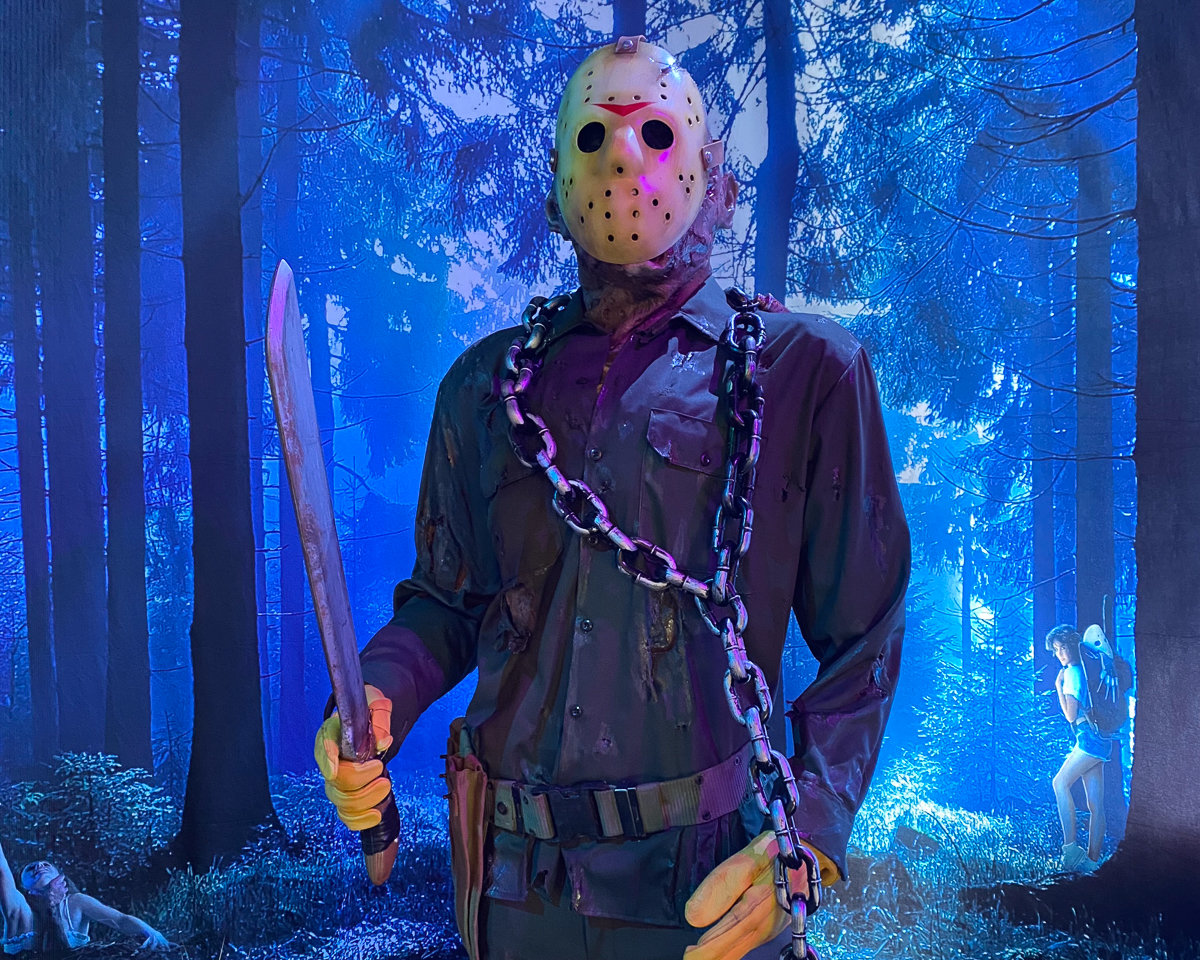 man with chains around his body and holding a knife in the forest